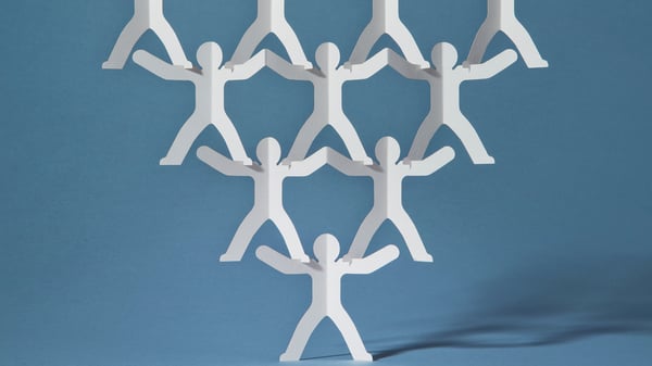 Paper men hold each other up in an upside down pyramid demonstrating clarity of message during Quarterly Business Reviews (QBRs)