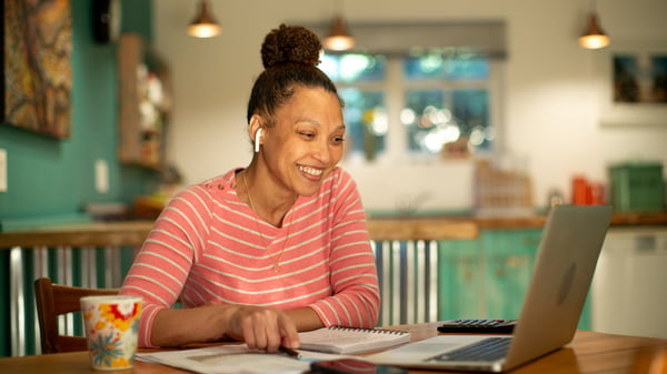 A woman is on her laptop with headphones and is learning about quarterly business reviews QBRs